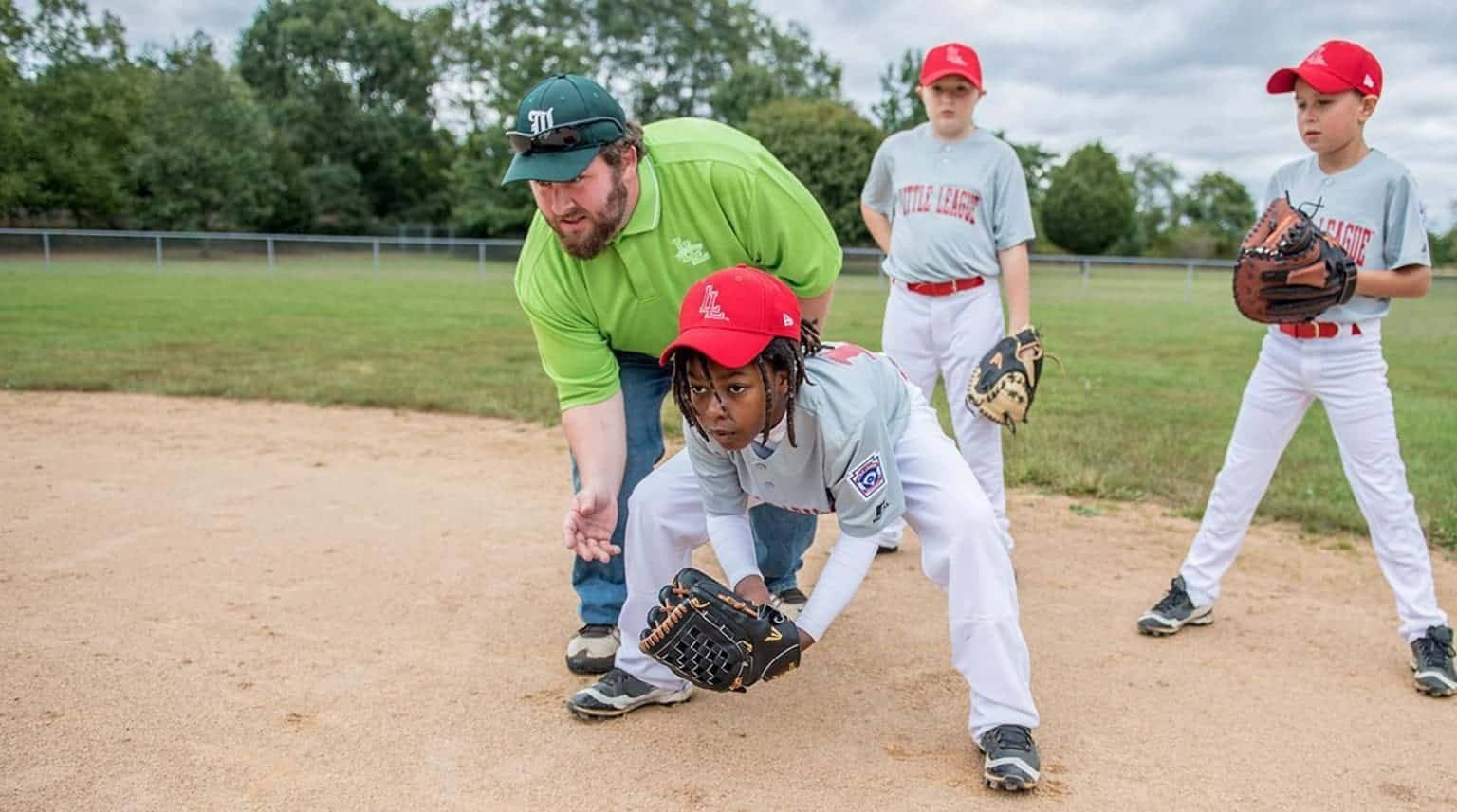 coaching ground balls to a youth baseball player